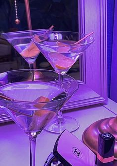 three martini glasses sitting on top of a counter