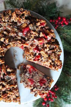 a white plate topped with a cake covered in nuts and cranberry toppings