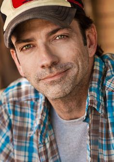 a man wearing a hat and looking at the camera with an intense look on his face