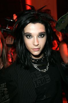 a woman with black hair and piercings standing in front of a group of people