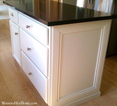 a kitchen island with black counter top and white cabinets