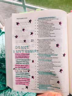 a hand holding an open bible with pink and green stars on it that says do not envy sinns