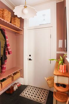 a hallway with pink walls and shelves filled with baskets on top of them, next to a white door