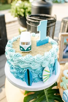 a blue and white birthday cake with a vw camper on the top is sitting on a table