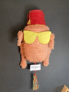 a stuffed animal with sunglasses and a hat hanging on the wall next to a sign