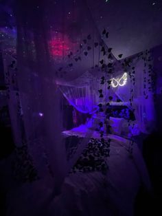 a bed with purple lights in a dark room filled with pillows and blankets on top of it