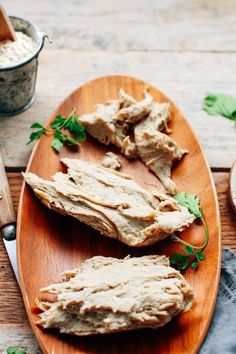 two pieces of bread on a wooden plate next to a knife and bowl of dip