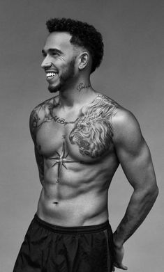 a black and white photo of a shirtless man with tattoos on his chest smiling