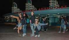 a group of people standing in front of a building at night with their arms up