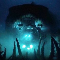 an underwater view of the front end of a vehicle with its lights on in deep water