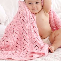 a baby wrapped in a pink blanket on top of a bed