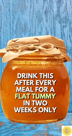 a glass jar filled with honey sitting on top of a wooden table next to a sign that says drink this after every meal for a flat tummy in two weeks only