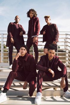 four young men are sitting on the steps wearing matching tracksuits and headphones