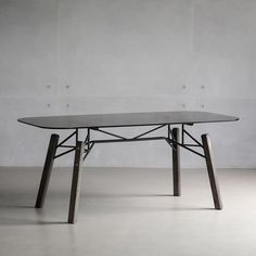 a glass table with wooden legs in an empty room