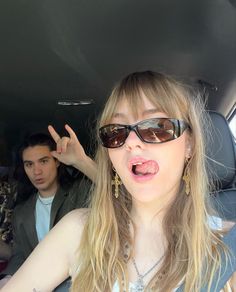 a woman in sunglasses making a funny face while sitting in the back seat of a car