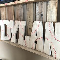 the word may spelled with baseball stitching in wood type letters on a wooden shelf