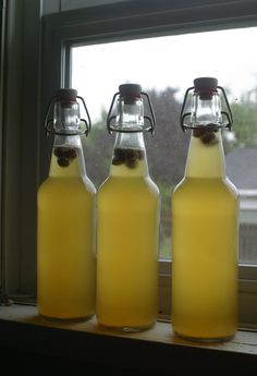 three glass bottles filled with liquid sitting on top of a window sill