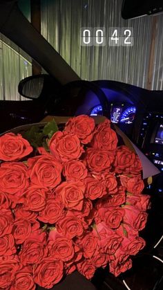 a bunch of red roses sitting on top of a black table next to a car