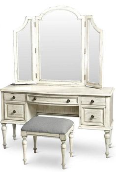 an antique white vanity with mirror and stool