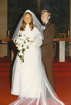 a man and woman standing next to each other in front of a church pews