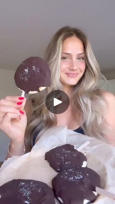 a woman holding up chocolate covered donuts in front of her face