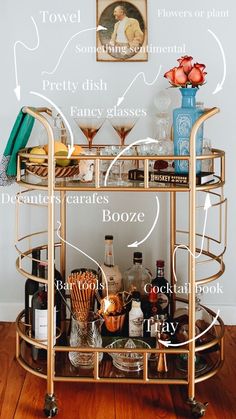 a gold bar cart filled with liquor bottles and glasses on top of a wooden floor