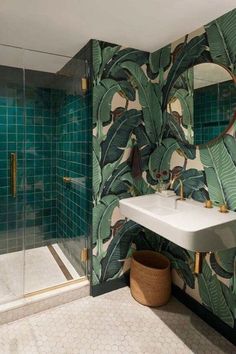 a green tiled bathroom with a mirror and sink in front of the shower area,