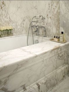 a bathroom with marbled walls and bathtub in the middle, along with soap dispensers