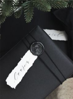 a black gift wrapped in paper with a wax seal on it and the name carr written on it