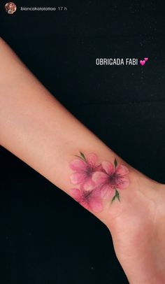 a small pink flower tattoo on the wrist