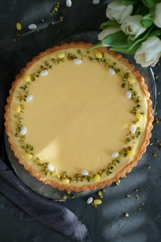 a pie sitting on top of a metal pan covered in frosting next to flowers