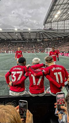 a group of men standing on top of a soccer field in front of a crowd