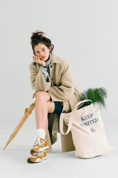 a woman sitting on top of a bag with an umbrella