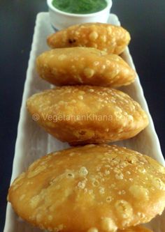 four doughnuts are lined up on a paper towel with dipping sauce in the background