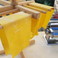 some yellow towels are hanging from a clothes line on a wooden rack next to a pasta maker