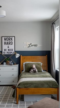 a bed sitting in a bedroom next to a dresser under a framed work hard sign