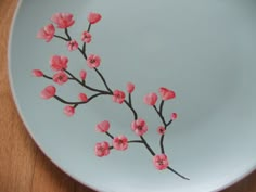 a white plate with pink flowers painted on the side, sitting on a wooden table