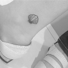 a small seashell tattoo on the ankle is shown in this black and white photo