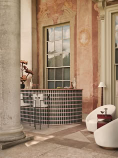 the interior of a building with large windows and white chairs in front of an arched window