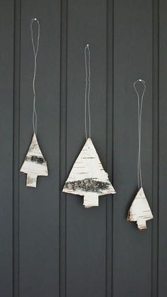 three pieces of wood are hanging from hooks on the wall, one is shaped like a christmas tree