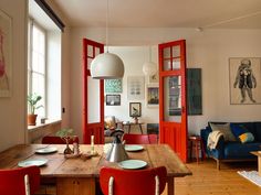 a dining room table with red chairs and an open door leading to the living room