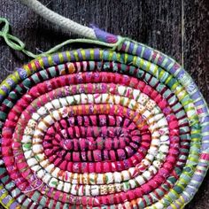 a multicolored round bag hanging on a wooden wall with string attached to it