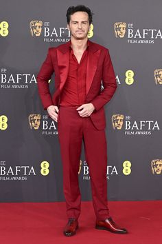 a man in a red suit standing on a red carpet