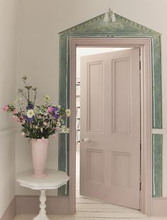 a vase filled with flowers sitting on top of a white table next to a doorway