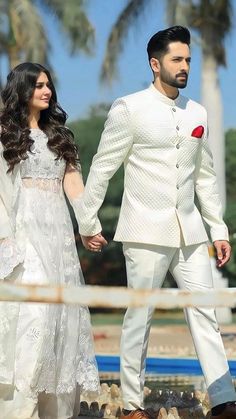 a bride and groom holding hands while walking