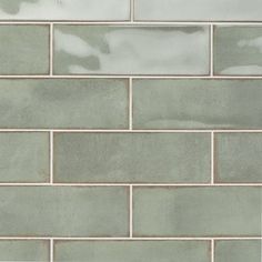 a close up view of a brick wall with light green and white tiles on it