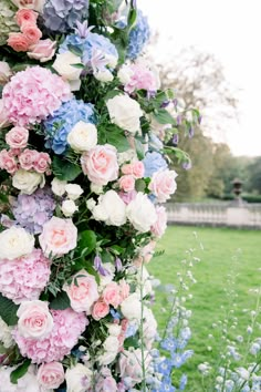 a bunch of flowers that are on the side of a pole with grass in the background