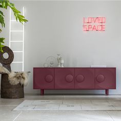 a living room with a red cabinet next to a potted plant