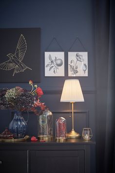 a table topped with vases filled with flowers next to two pictures on the wall