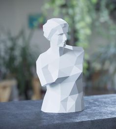 a white sculpture sitting on top of a table next to a potted green plant